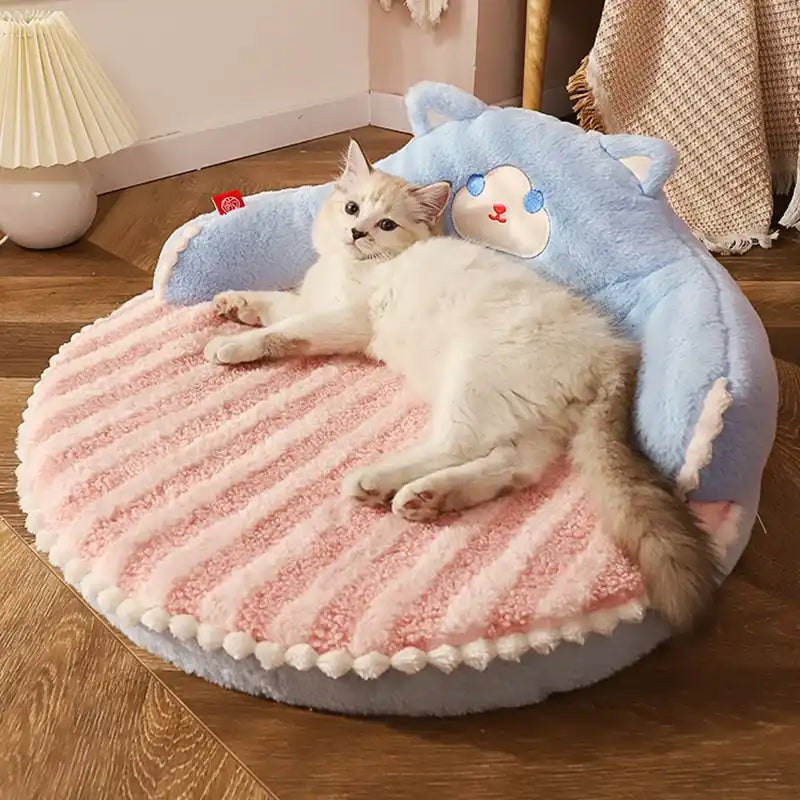 Cat lying on a round, plush pet bed with cartoon cat face design in a cozy room.
