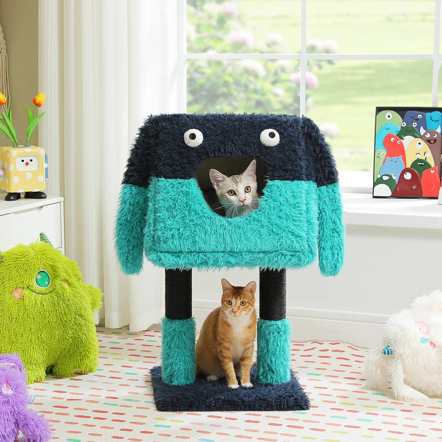 Two cats playing with a colorful monster-shaped cat tree in a room with toys and a window.