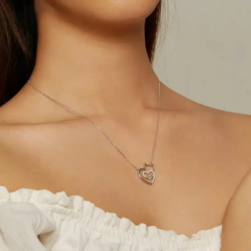 Necklace with a heart-shaped pendant worn by a person in a white top.