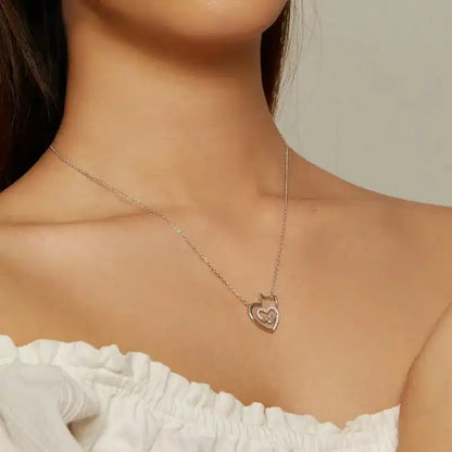 Necklace with a heart-shaped pendant worn by a person in a white top.