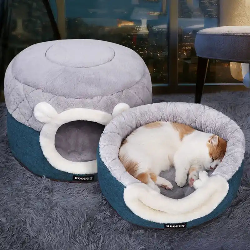 Cat sleeping in a gray and blue pet bed with a fluffy texture.