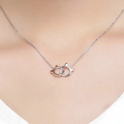 Silver necklace with a cat-shaped pendant on a person's neck against a neutral background