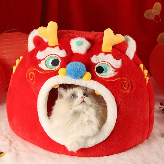 Cat peeking out from a red dragon-shaped cat bed with colorful accents on a red background.