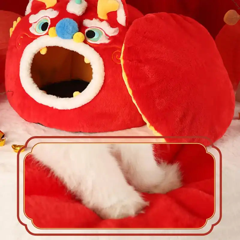 Red lion cat bed with cat paws on a pillow on a light pink background.
