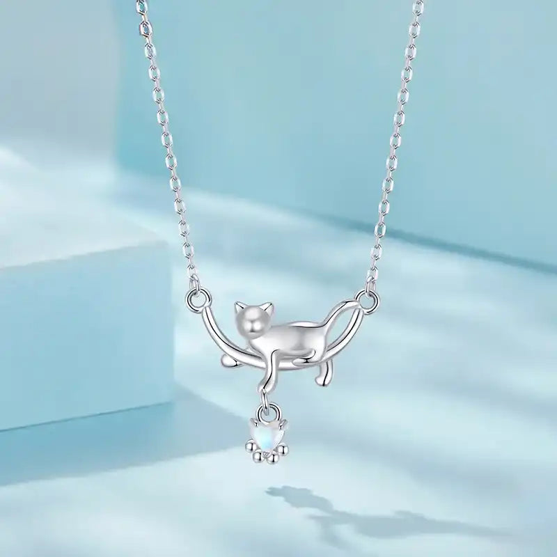 Silver cat-shaped necklace with a small pendant on a light blue background