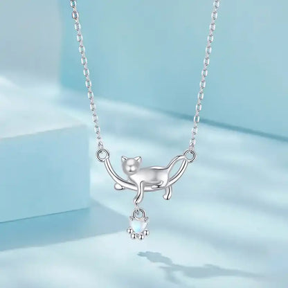 Silver cat-shaped necklace with a small pendant on a light blue background