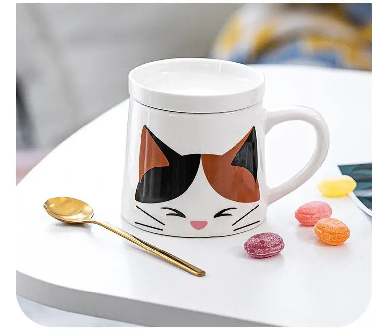 Cat-shaped mug with a spoon and candies on a white surface