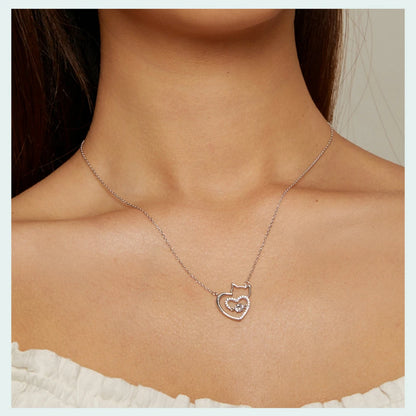 Silver necklace with a heart-shaped cat pendant on a person's neck.