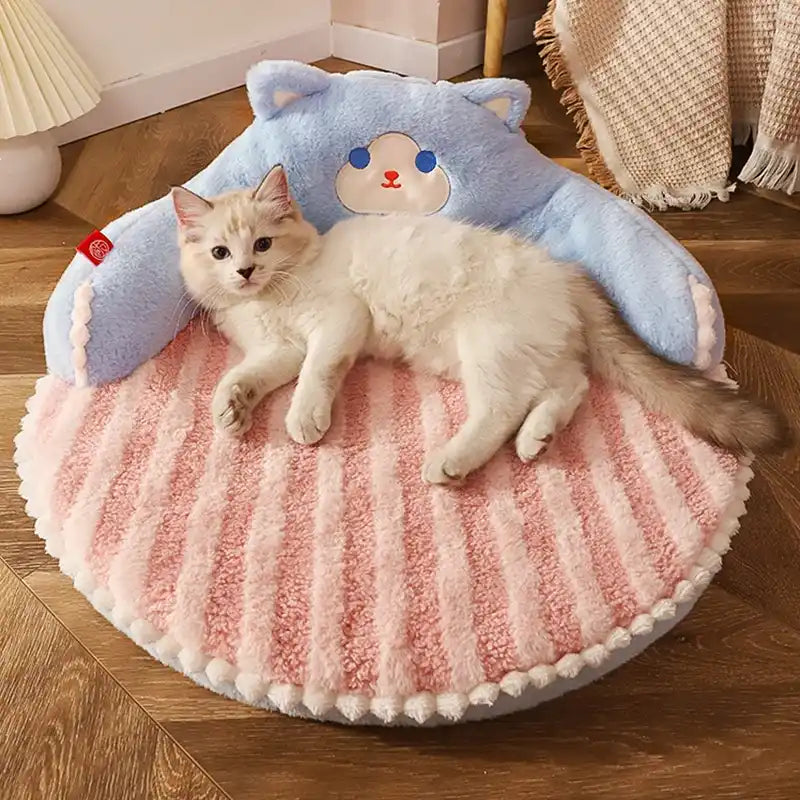Cat lying on a pink and blue cushion with cat design on a wooden floor.