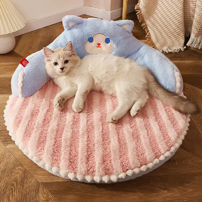 Cat lying on a pink and blue cushion with cat design on a wooden floor.