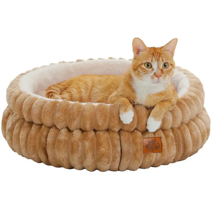 Cat laying in a caramel colored ribbed cat bed with a white background