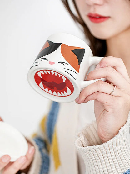 Person holding a mug with a cat face design