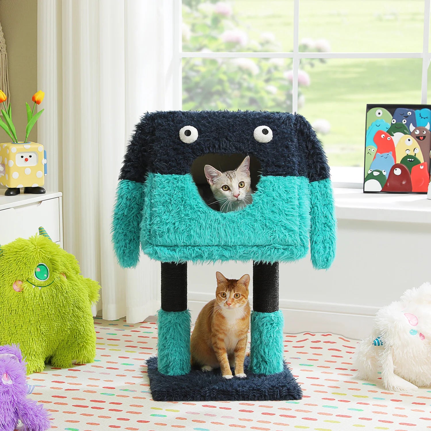 Two cats playing with a colorful monster-shaped cat tree in a room with toys and a window.