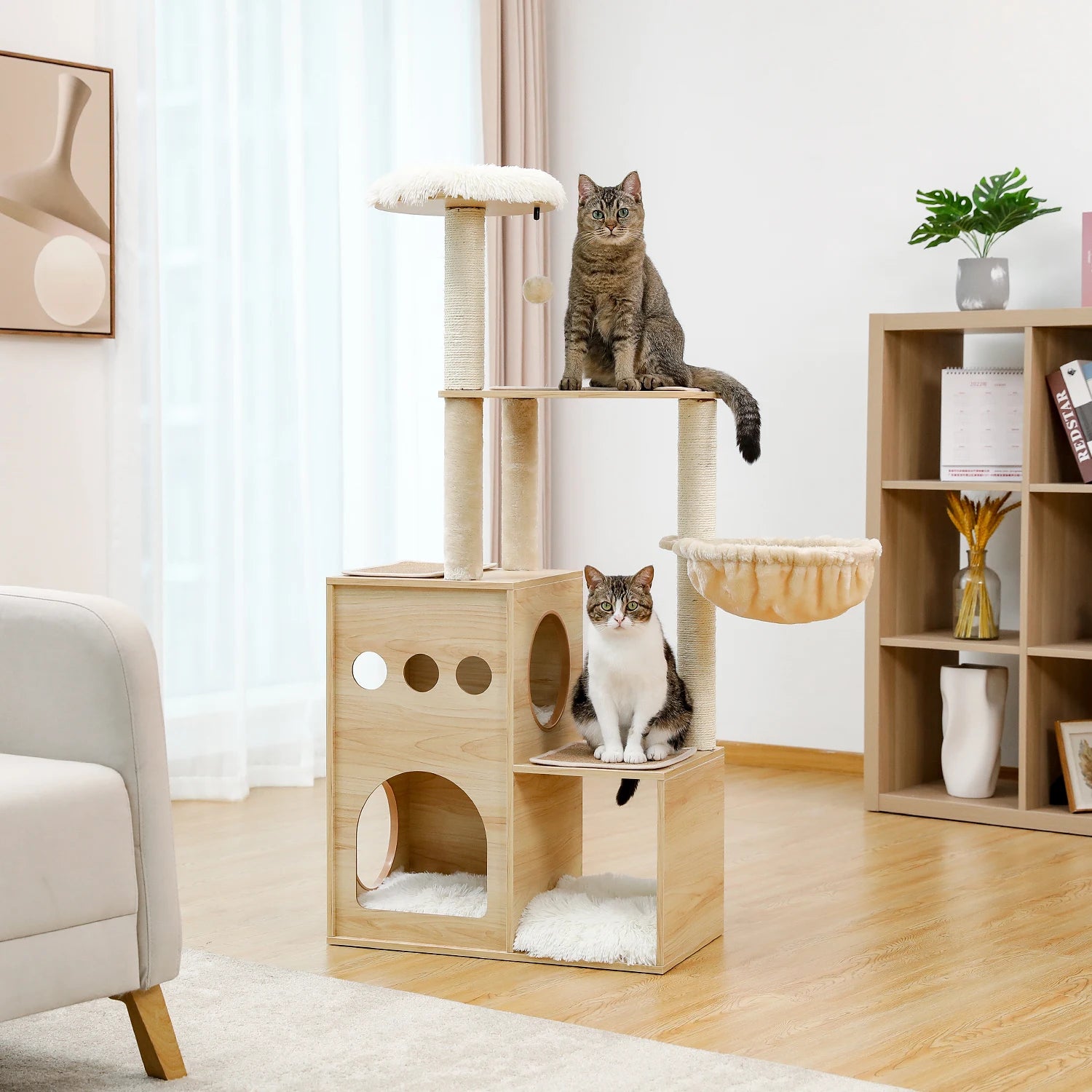 Two cats sitting on a wooden cat tree in a living room setting.